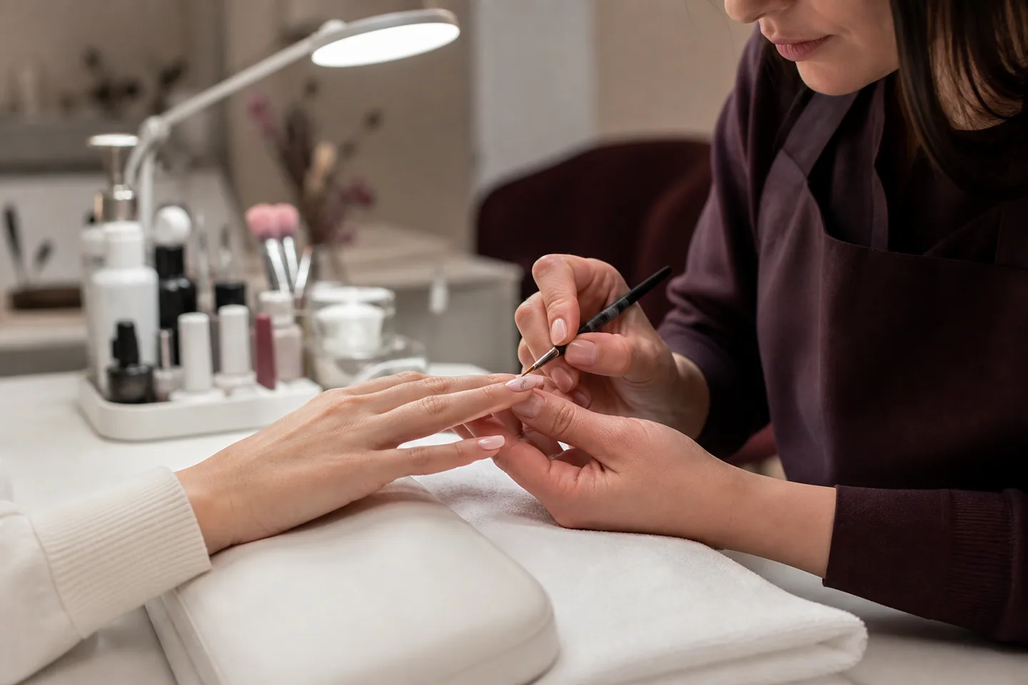 Nageldesignerin gestaltet in einem professionellen Studio eine Maniküre