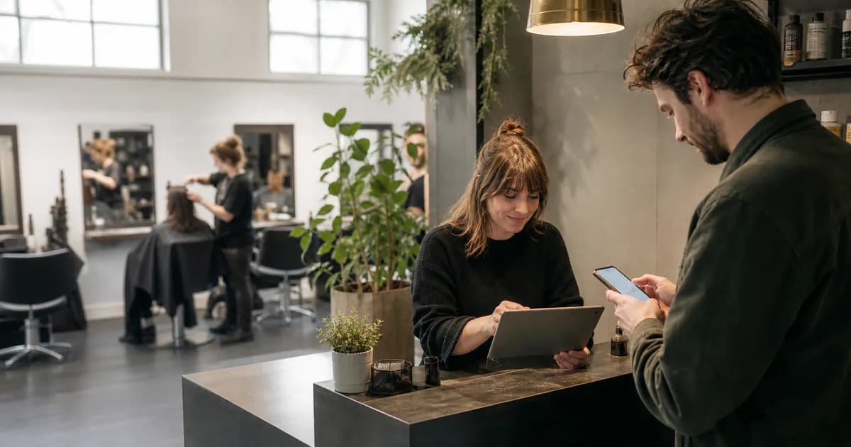 Salonempfang mit Smartphone-Buchung und gemeinsamem digitalen Kalender in einem modernen deutschen Friseursalon